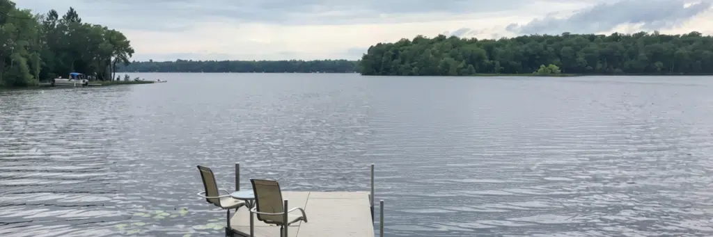 Scenic view of Lake Minnewawa with a wooden dock and calm water under a clear sky.